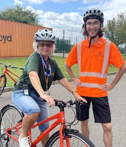 Lorraine on her bike with a man standing next to her smiling.